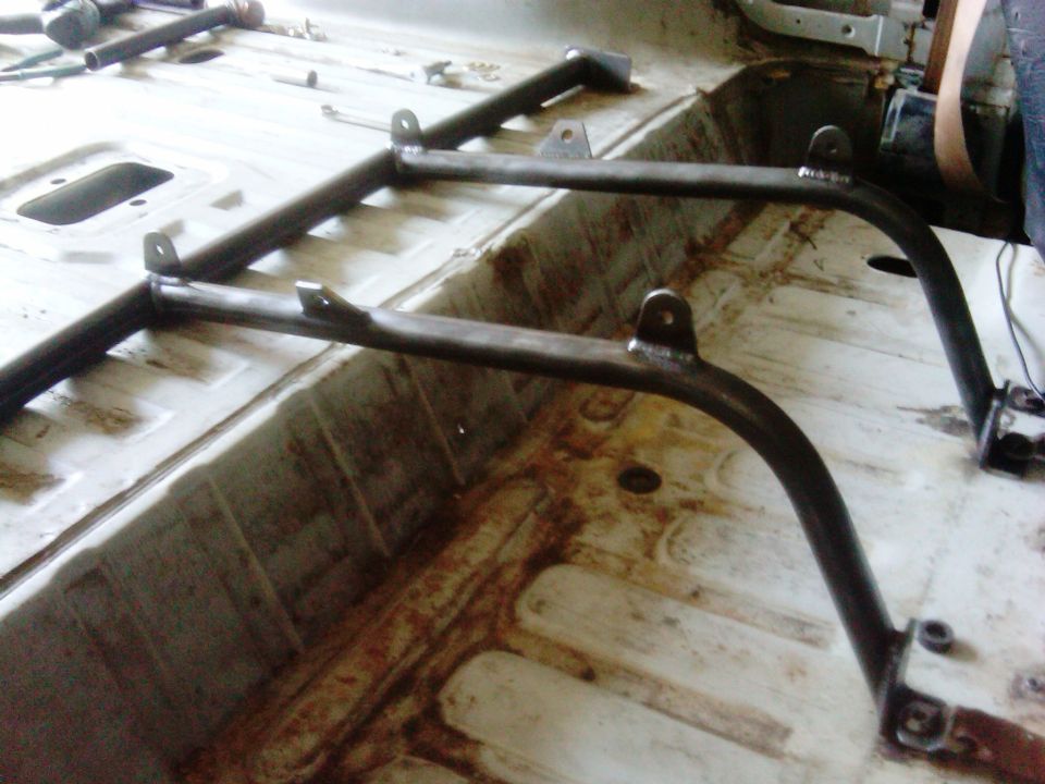 Roll cage installed in a vehicle's interior, showing metal tubing and mounting points on the floor