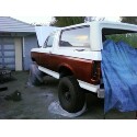 1989 Ford Bronco - This SUV appears to be undergoing some body work, with its hood and rear section open and a blue tarp covering part of the vehicle.