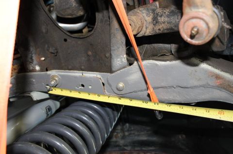 1987 Ford Bronco - A close-up view shows a suspension part being measured with a tape measure, indicating a focus on its dimensions.