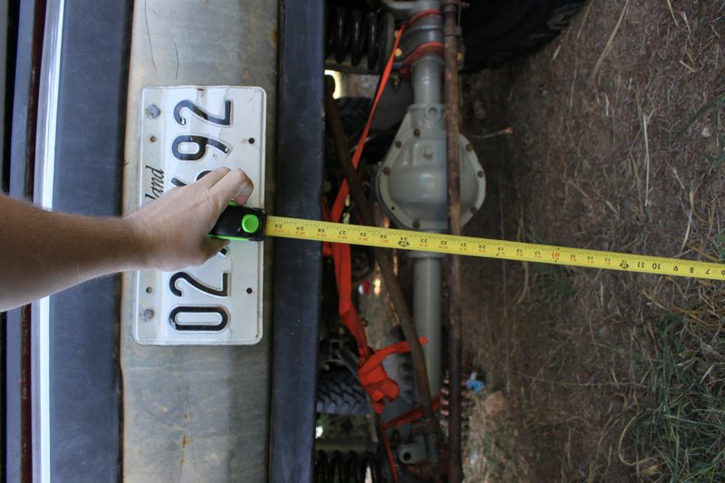License plate with '02 92' and 'land' visible, next to a measuring tape and a vehicle's rear axle
