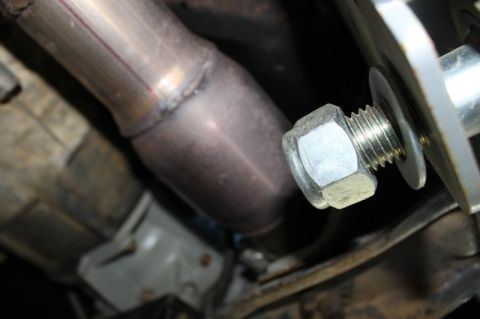 1987 Ford Bronco - Exhaust pipe connection detail with a prominent bolt and washer visible.