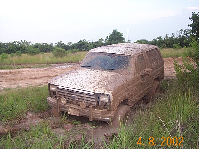Muddy SUV stuck in a muddy field. The front grille and headlights are visible