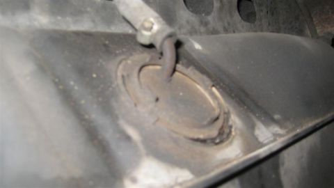 1968 Ford Ranchero - A close-up view of a vehicle's undercarriage shows a metal exhaust hanger bracket with visible rust and wear.