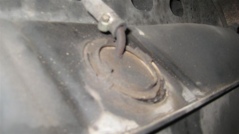 close-up of a rusty exhaust hanger bracket on a vehicle underside