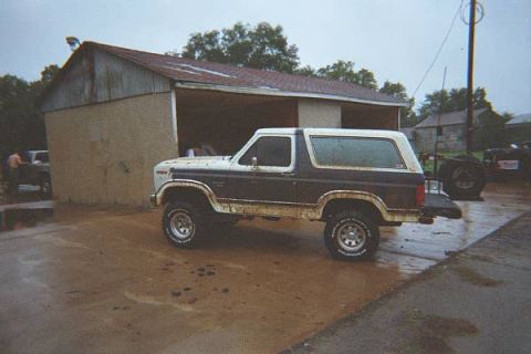 1986 Ford Bronco - This 1986 Ford Bronco is seen parked on a wet surface next to a building.