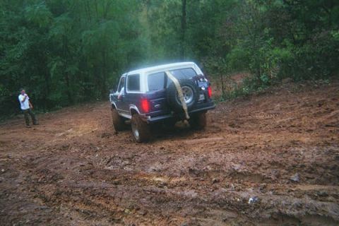 1986 Ford Bronco - Ford Bronco navigating a challenging muddy terrain on an offroad trail.