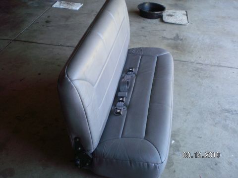 1996 Ford Bronco - A gray car seat with seatbelts is shown on a concrete floor, with a black pan and some rags in the background.