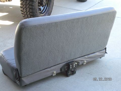 1996 Ford Bronco - A gray car seat is shown with a visible latch mechanism, and a tire from another vehicle is in the background.
