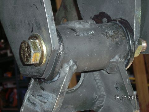 1996 Ford Bronco - Tight close-up of a welded leaf spring hanger and shackle joint, with the spring eye bushing sleeve passing through flat steel shackle plat…