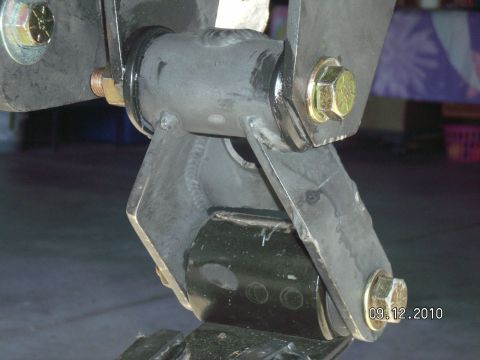 1996 Ford Bronco - Close-up of a black-painted leaf spring shackle assembly bolted to a frame hanger with yellow zinc-plated hex bolts, photographed under the…