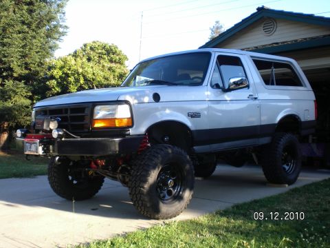 1996 Ford Bronco - This lifted Ford Bronco is parked in front of a house and garage on a sunny day.