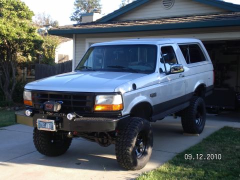 1996 Ford Bronco - A lifted 1996 Ford Bronco is parked in front of a garage.