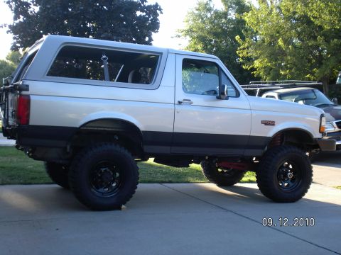 1996 Ford Bronco - This lifted 1996 Ford Bronco is shown from the side, with another vehicle in the background.