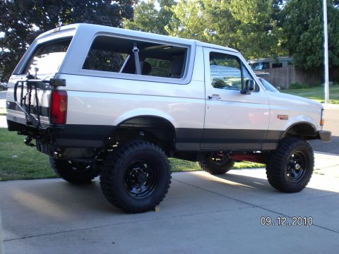 1996 Ford Bronco - A lifted 1996 Ford Bronco is parked on a concrete driveway, showing its off-road modifications.
