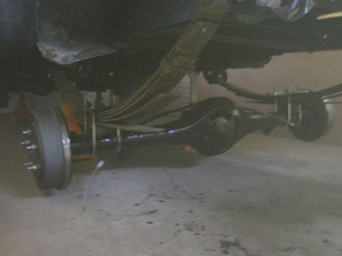 1979 Ford Bronco - Close-up view of a vehicle's rear axle, leaf springs, and drum brake components.
