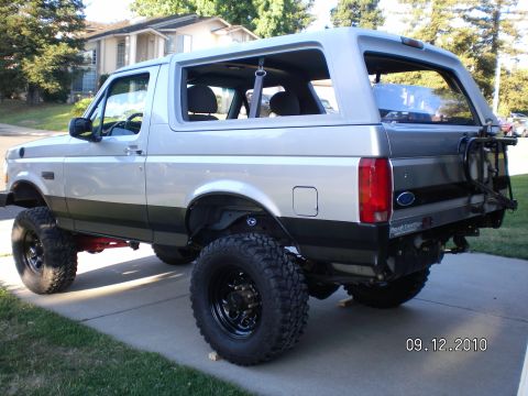 1996 Ford Bronco - This lifted 1996 Ford Bronco is shown from the rear 3/4 angle, parked on a suburban driveway.