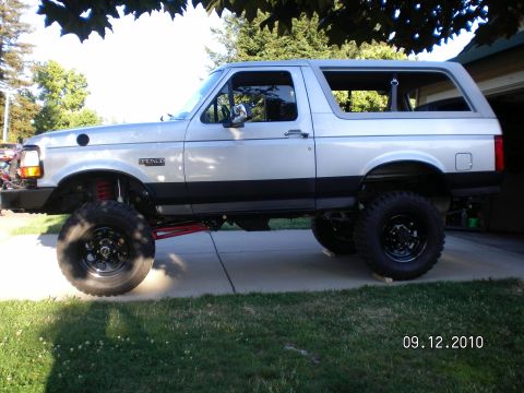 1996 Ford Bronco - This lifted 1996 Ford Bronco is parked on a driveway with grass and trees in the background.