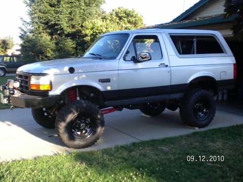 1996 Ford Bronco - A silver Ford Bronco is shown lifted with large tires and an aftermarket bumper.