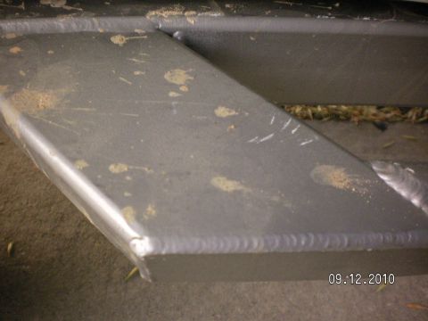 1996 Ford Bronco - Close-up of a fabricated gray steel rocker guard or nerf-bar step welded to a boxed frame rail, with a continuous stitch weld bead running…