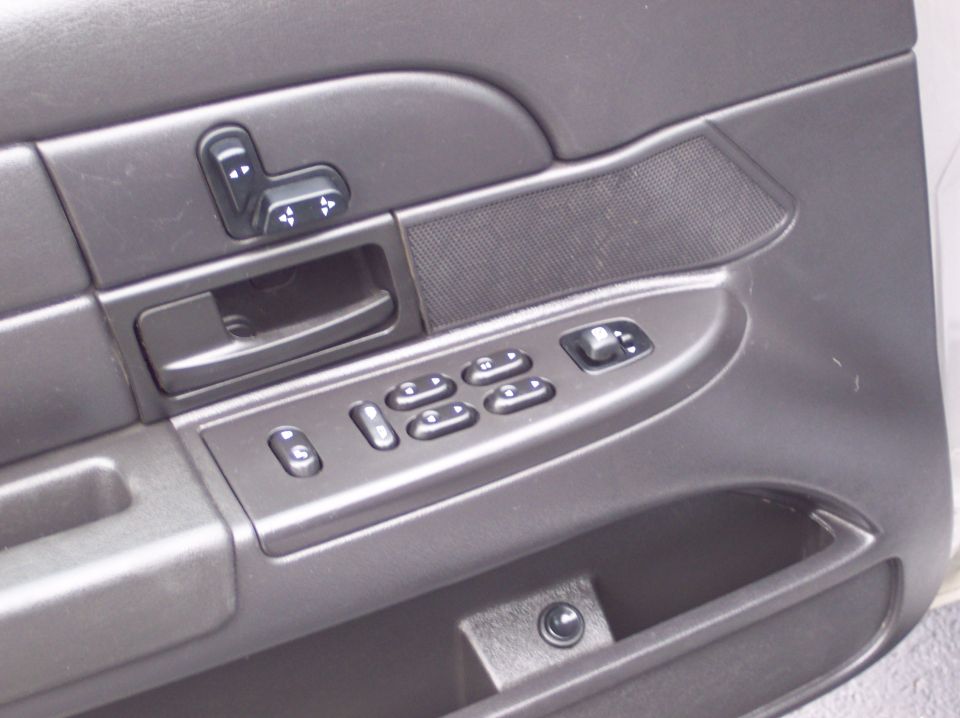 Interior door panel with power window and seat controls, dark gray plastic