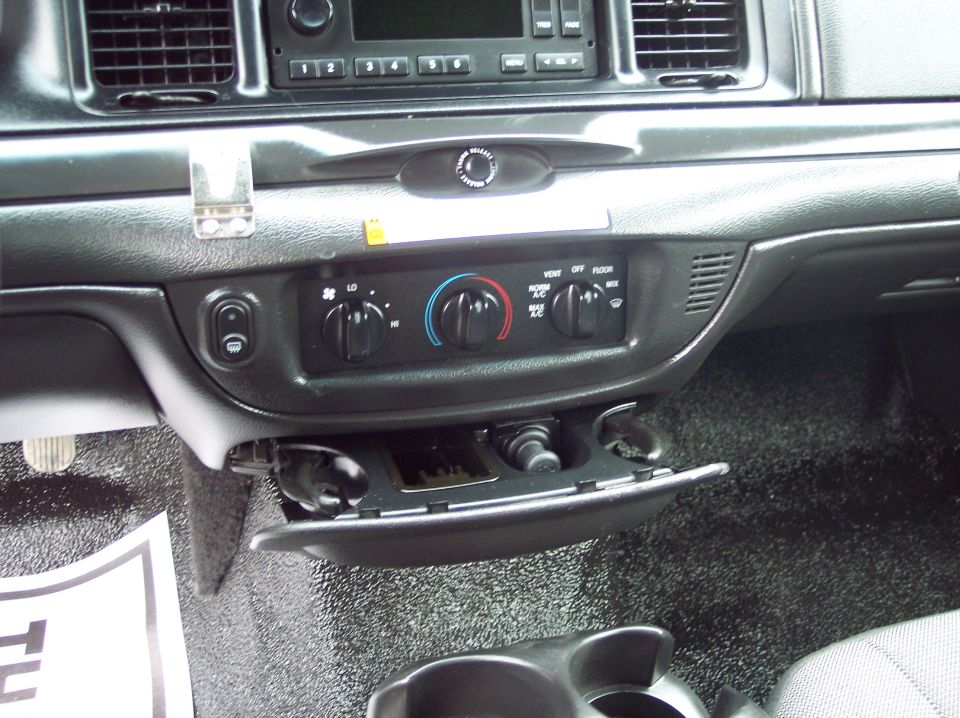 Dashboard interior of a police car with climate controls and an open storage compartment