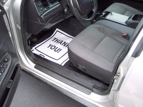 2001 Ford Crown Victoria - The interior of a police car features a 'Thank You!' floor mat and a driver's seat.