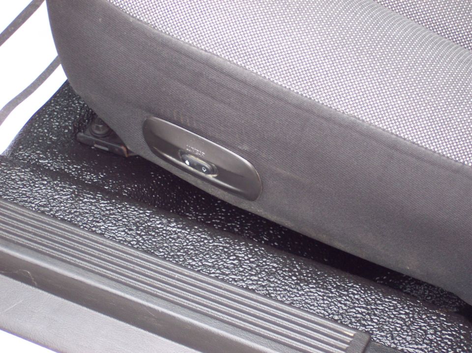 Close-up of a car's fabric seat with a black plastic power seat adjustment control panel