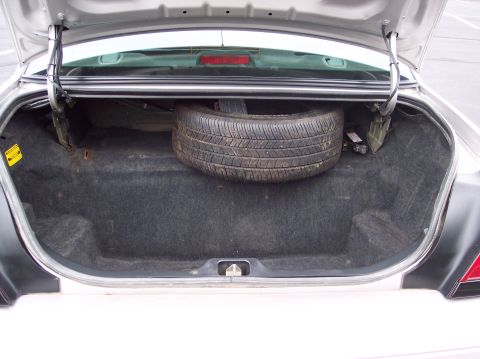 2001 Ford Crown Victoria - The trunk of a 2001 Ford Crown Victoria is open, revealing the spare tire and jack stored within.