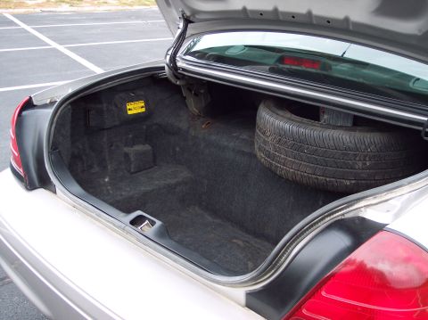 2001 Ford Crown Victoria - The trunk of a 2001 Ford Crown Victoria contains a spare tire and carpeted storage compartments.