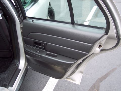 2001 Ford Crown Victoria - The interior door panel of a silver sedan is shown, with a glimpse of another vehicle outside.