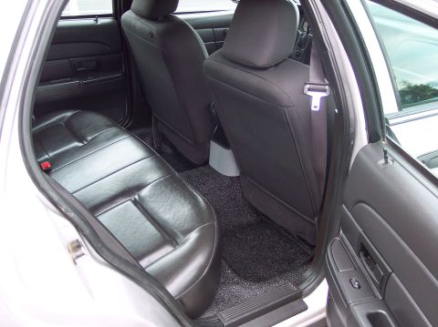 2001 Ford Crown Victoria - Rear interior view of a silver sedan, showing black leather seats and door panel.