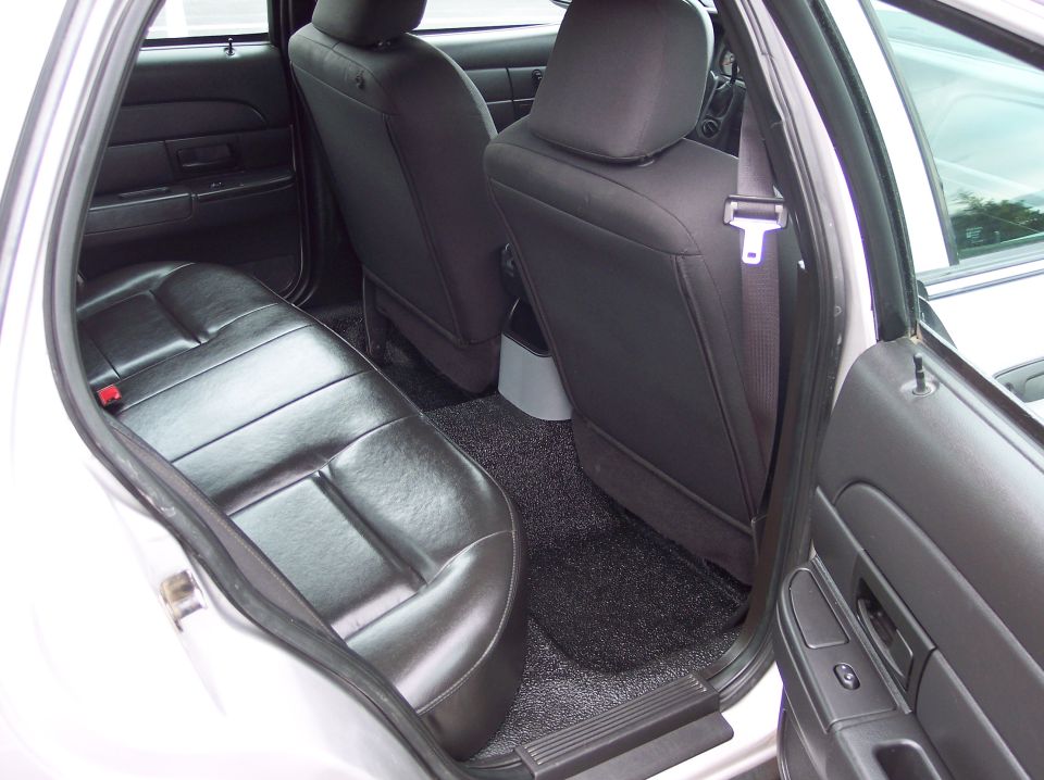 Interior rear seats and door panel of a silver sedan, black leather seats, black carpet