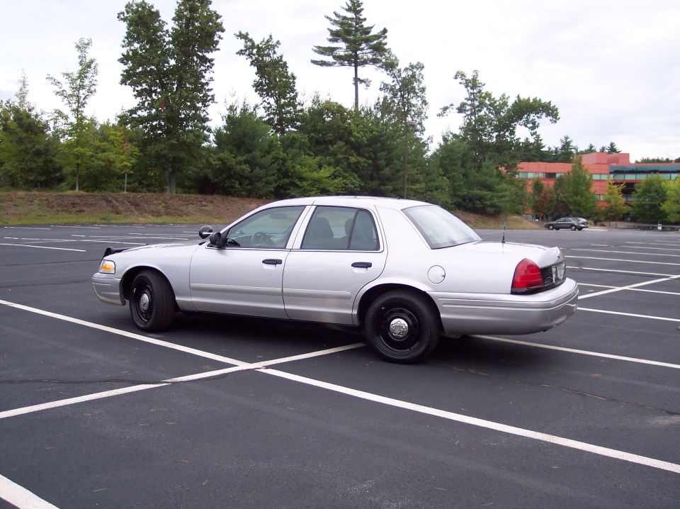 Silver police car parked in a lot, viewed from the rear quarter