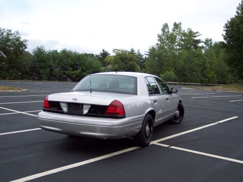 2001 Ford Crown Victoria - Rear view of a silver 2001 Ford Crown Victoria sedan parked in an empty lot.