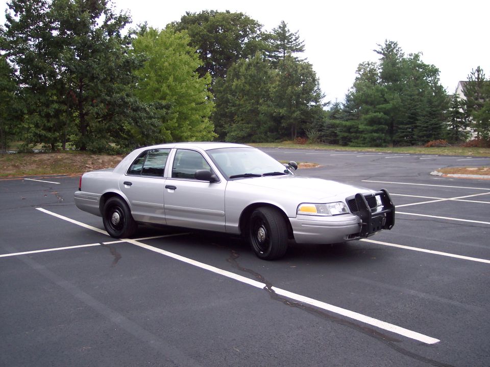 Silver 2001 Ford Crown Victoria police car with push bumper parked in lot
