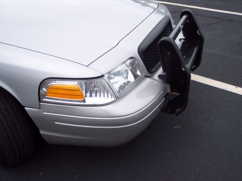 2001 Ford Crown Victoria - Close-up of the front of a silver 2001 Ford Crown Victoria, showing the headlights, grille, and a black push bar.