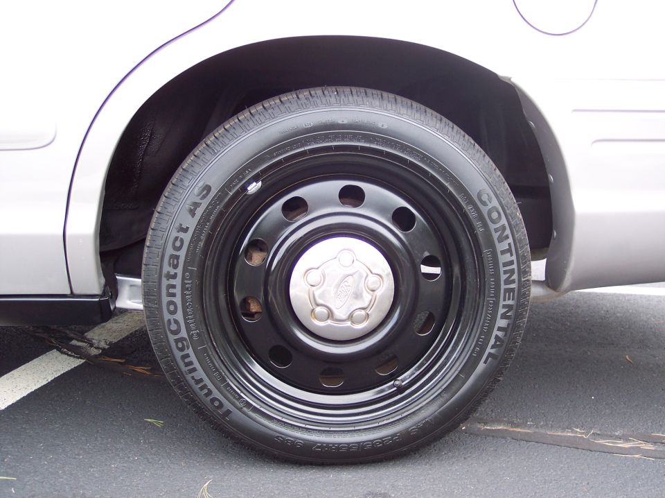 2001 Ford Crown Victoria steel wheel with black hubcap and Continental TouringContact AS tire