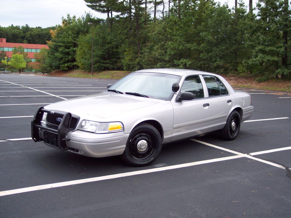Silver 2001 Ford Crown Victoria police car with push bumper, parked in a lot