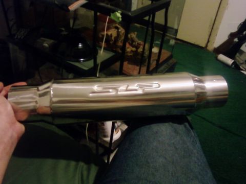 1995 Ford Bronco - A person holds a chrome SLP exhaust muffler, likely for a vehicle modification.