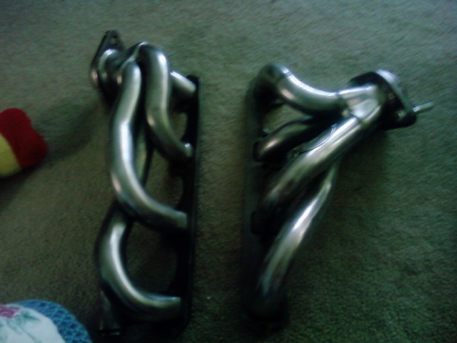 Two chrome exhaust manifolds on a carpeted surface