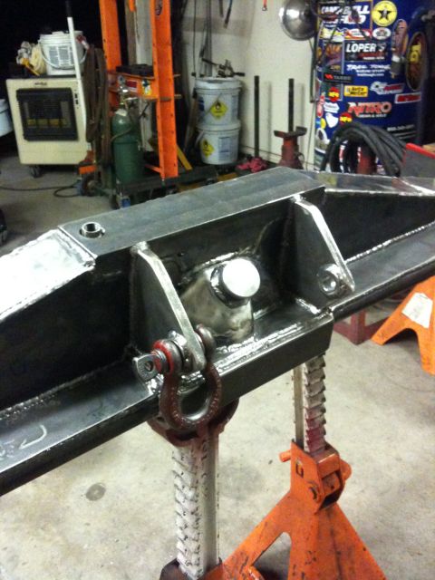 Suzuki Samurai - Custom fabricated steel axle housing with a shackle mount is shown supported by jack stands in a workshop.