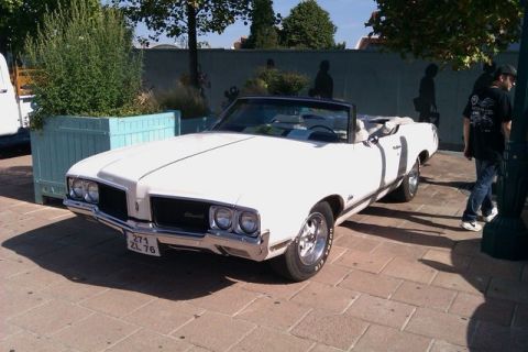 1991 Ford LTD Crown Victoria - A white convertible with a black top is parked on a brick patio, with a person standing nearby.