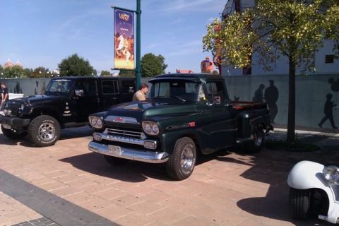 1991 Ford LTD Crown Victoria - A 1959 Chevrolet Apache pickup truck is parked beside a black Jeep, with a banner overhead.