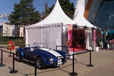 1991 Ford LTD Crown Victoria - A blue convertible sports car with white racing stripes is displayed under a tent.