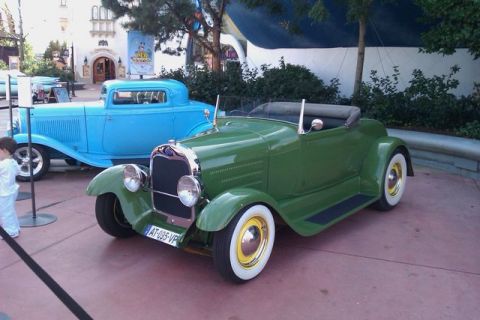 1991 Ford LTD Crown Victoria - A green convertible roadster is parked next to a blue coupe, with a child standing nearby.