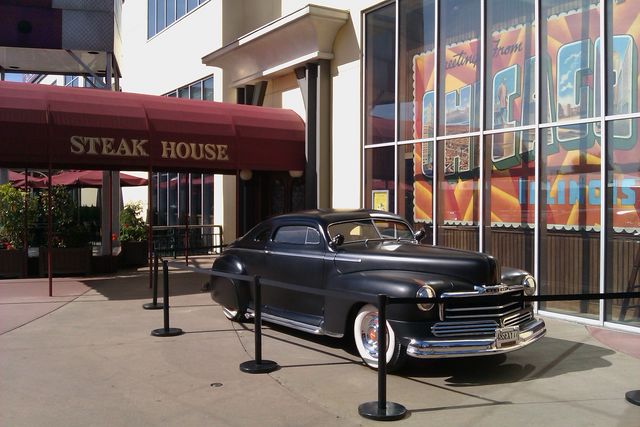 1946 Ford coupe parked outside a steak house with large windows displaying graphics