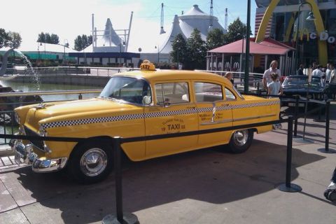 1991 Ford LTD Crown Victoria - A classic yellow taxi is parked in front of a McDonald's and other attractions.