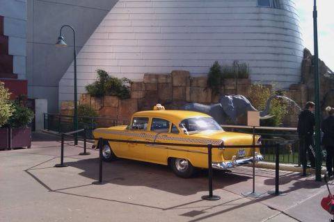 1991 Ford LTD Crown Victoria - A yellow taxi, resembling a 1955 Chevrolet, is displayed with a backdrop of faux rocks and an elephant statue.