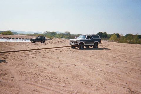 1986 Ford Bronco - A 1986 Ford Bronco is seen in a dry riverbed with another SUV in the background.