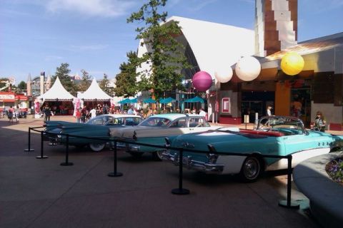 1991 Ford LTD Crown Victoria - A row of vintage cars, including a convertible, are displayed outdoors in front of buildings.